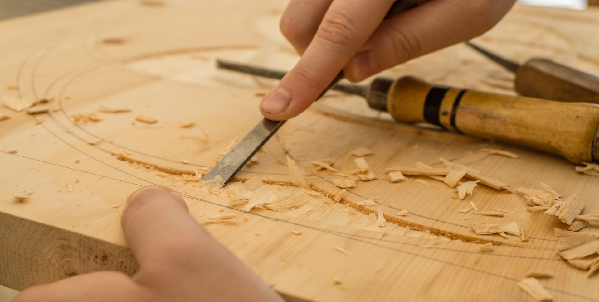 Skilled carpenter carving intricate design into wooden piece with woodworking tool.