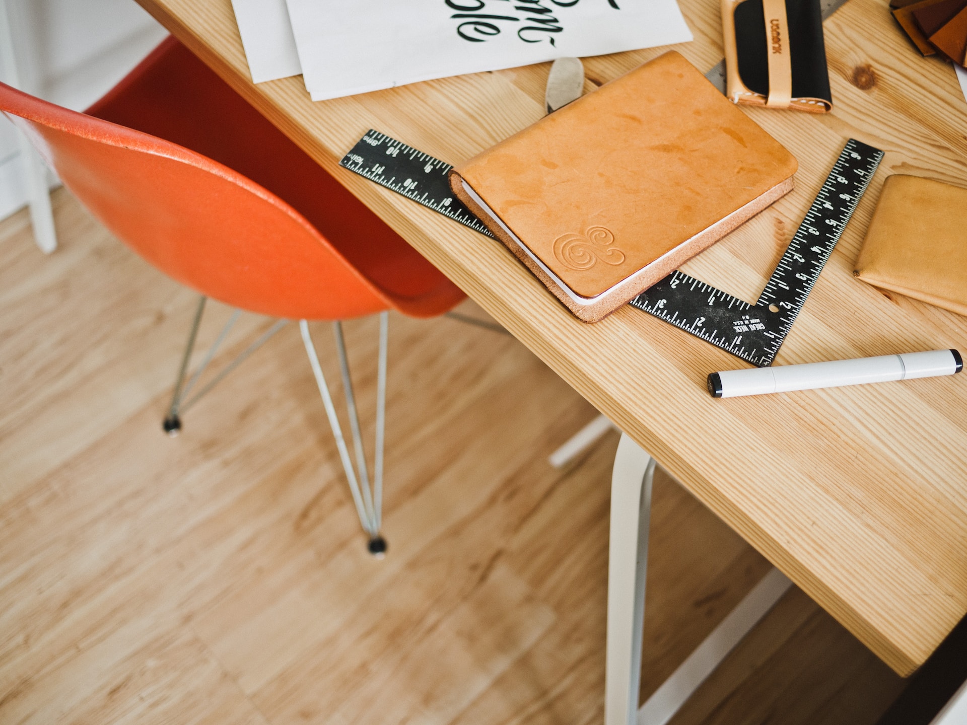 An aesthetically pleasing wooden desk adorned with essential supplies like a laptop, ruler, pen, and notebook, ideal for productive work.