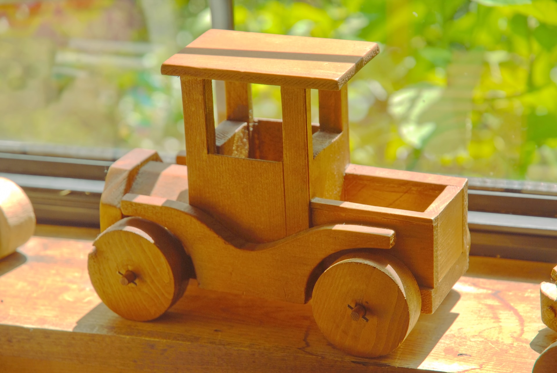 A small wooden toy car perched on a windowsill